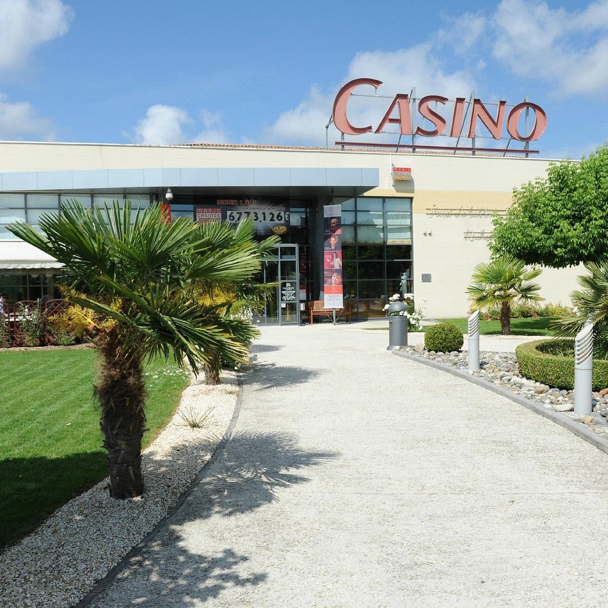 A casino building with a prominent 'CASINO' sign, a glass entrance, and a gravel pathway leading to the entrance.