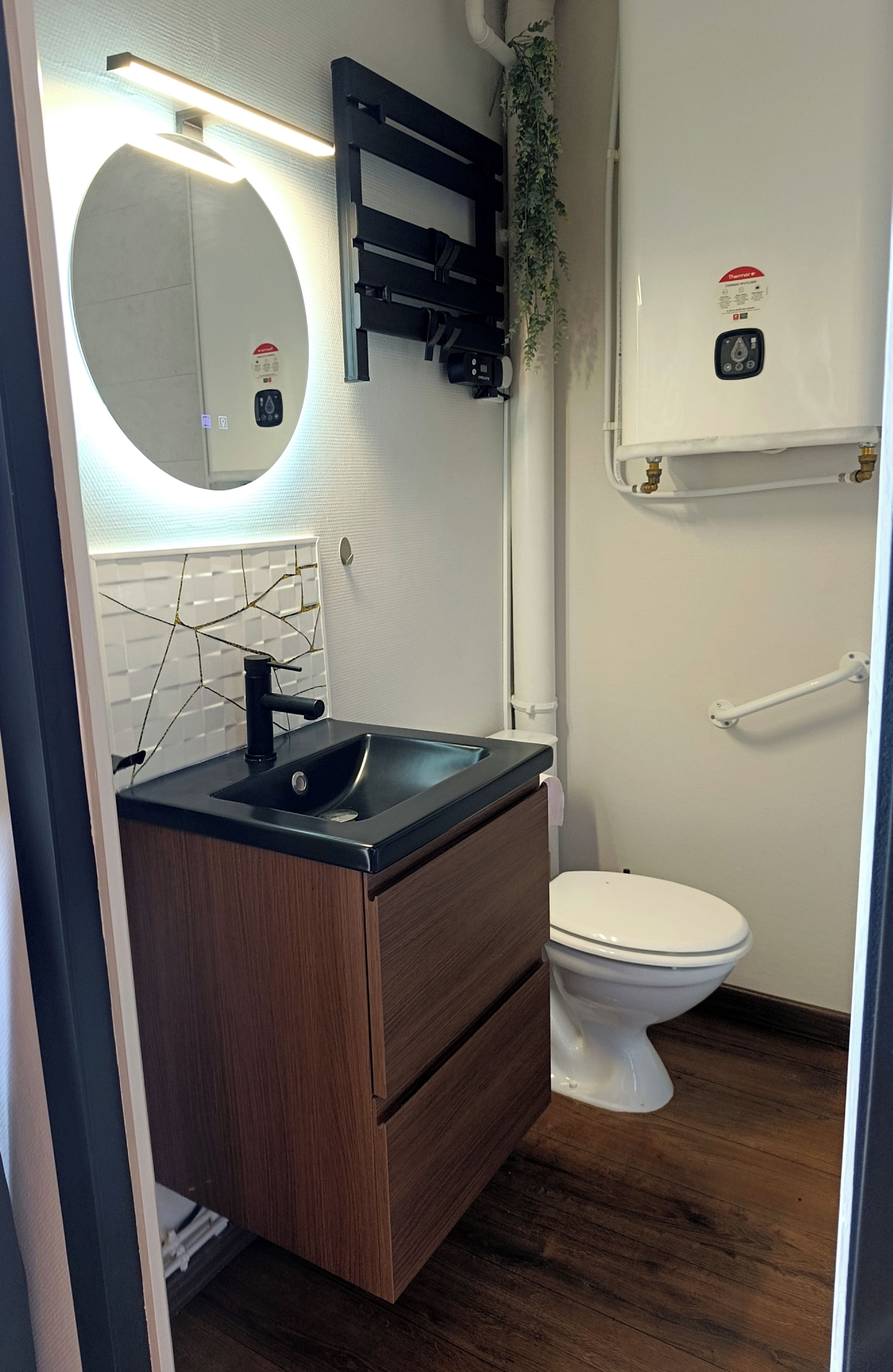 Un baño con lavamanos, espejo, inodoro y toallero.