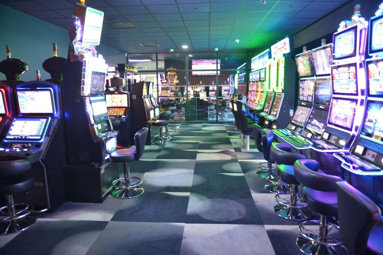 L’intérieur d’un casino, avec des machines à sous, des tabourets de bar et un motif à carreaux sur le sol.