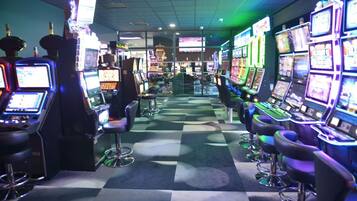 L’intérieur d’un casino, avec des machines à sous, des tabourets de bar et un motif à carreaux sur le sol.