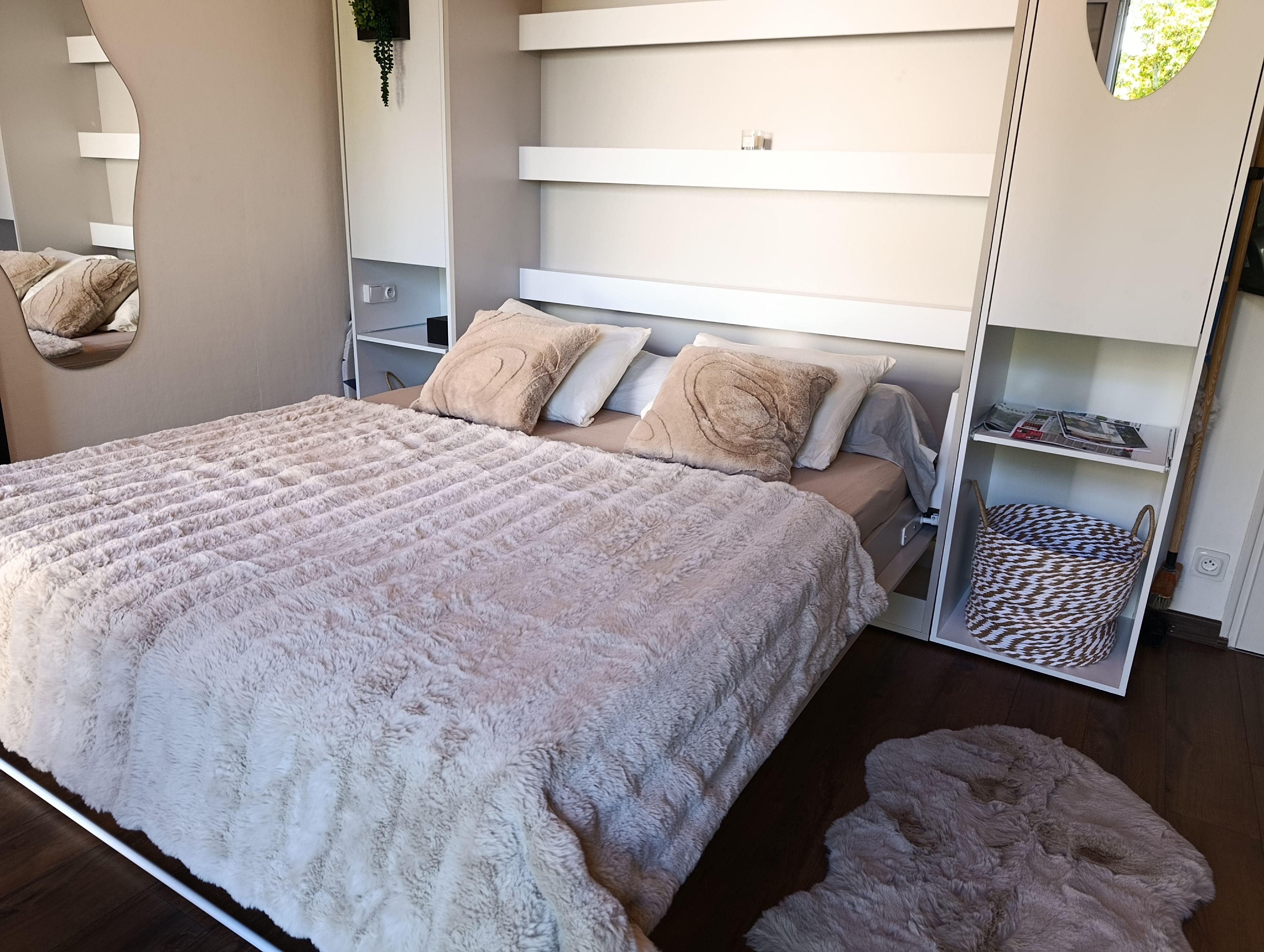 Une chambre à coucher moderne avec un grand lit, des étagères intégrées et un miroir décoratif.