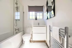 A modern bathroom with a bathtub, toilet, and a vanity with a mirror. - Elegant Moor Park Home With Golf Club &amp; London City Centre Access (Northwood)