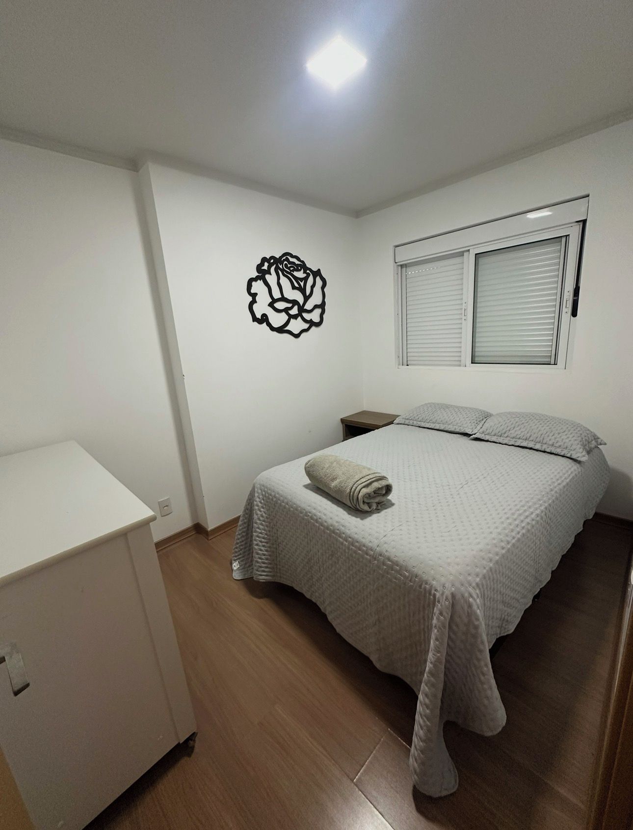 A bedroom with a bed, a nightstand, a dresser, and a wall decoration.