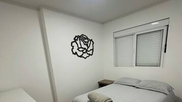 A bedroom with a bed, a nightstand, a dresser, and a wall decoration.