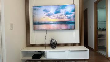 Un saló modern amb un televisor de pantalla plana muntat a la paret, una obra decorativa i una catifa estampada al terra.
