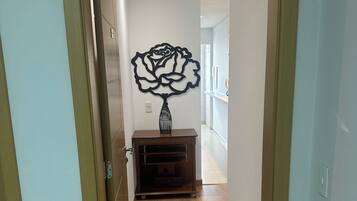 Un couloir doté d’un plancher en bois, d’un élément décoratif fixé au mur et d’une petite armoire en bois.