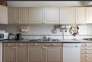 A kitchen with white cabinets, a microwave, a toaster, a sink, and hanging utensils. - Apartment 'Vilamoura Garden View' with Shared Pool, Wi-Fi and Air Conditioning (Quarteira)