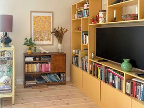 Quarto com estante, televisão e quadro na parede.