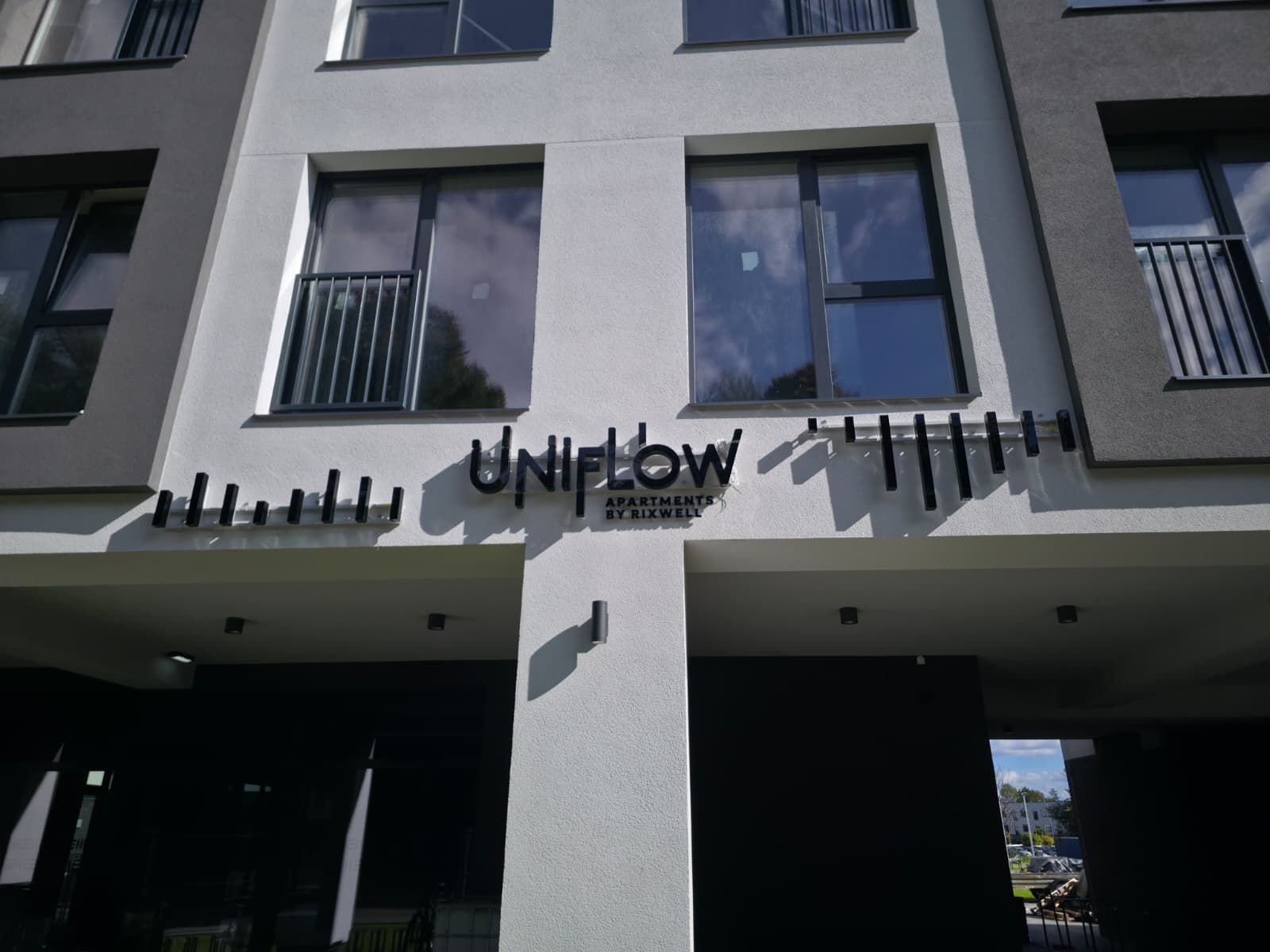 A building with a sign that reads 'UNIFLOW APARTMENTS BY RIXWELL'.