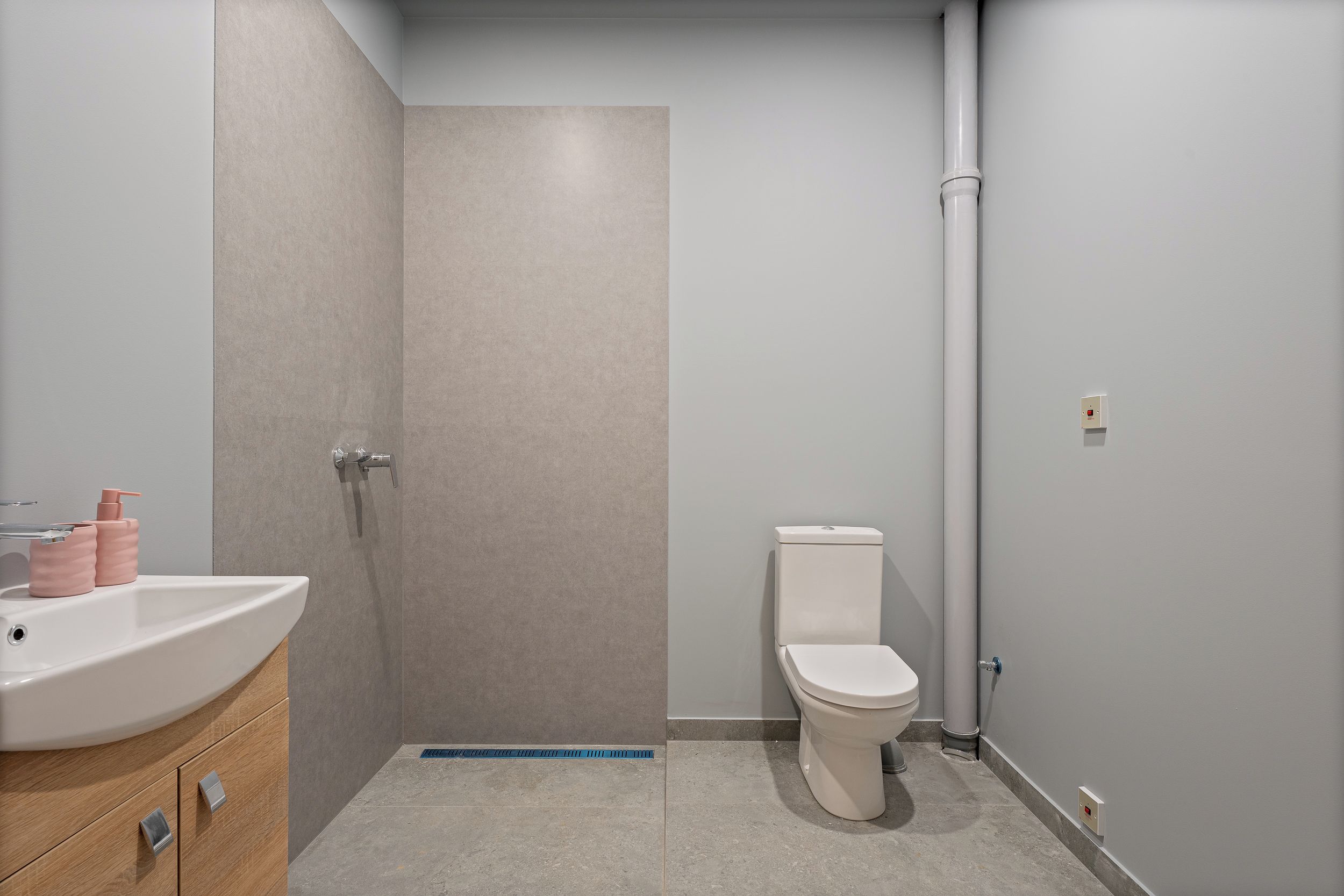 A modern bathroom with a shower, toilet, and sink.