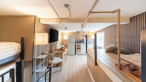 Een knus hotelkamer met een bed, een bureau, een stoel, een kleine kitchenette en een televisie.