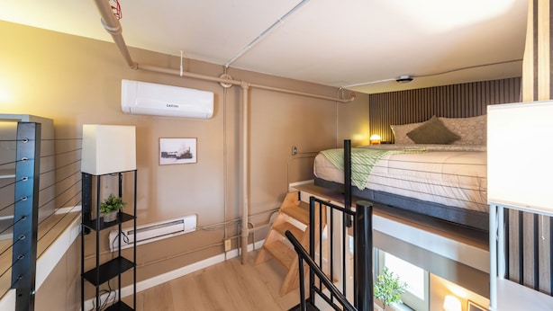 Een moderne, compacte kamer met stapelbedden, een ingebouwd bureau en een wandairconditioner.