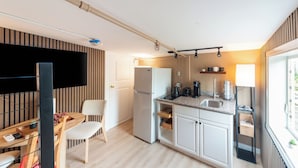 Een compacte keuken met een koelkast, fornuis en een klein eethoekje met een stoel en tafel.