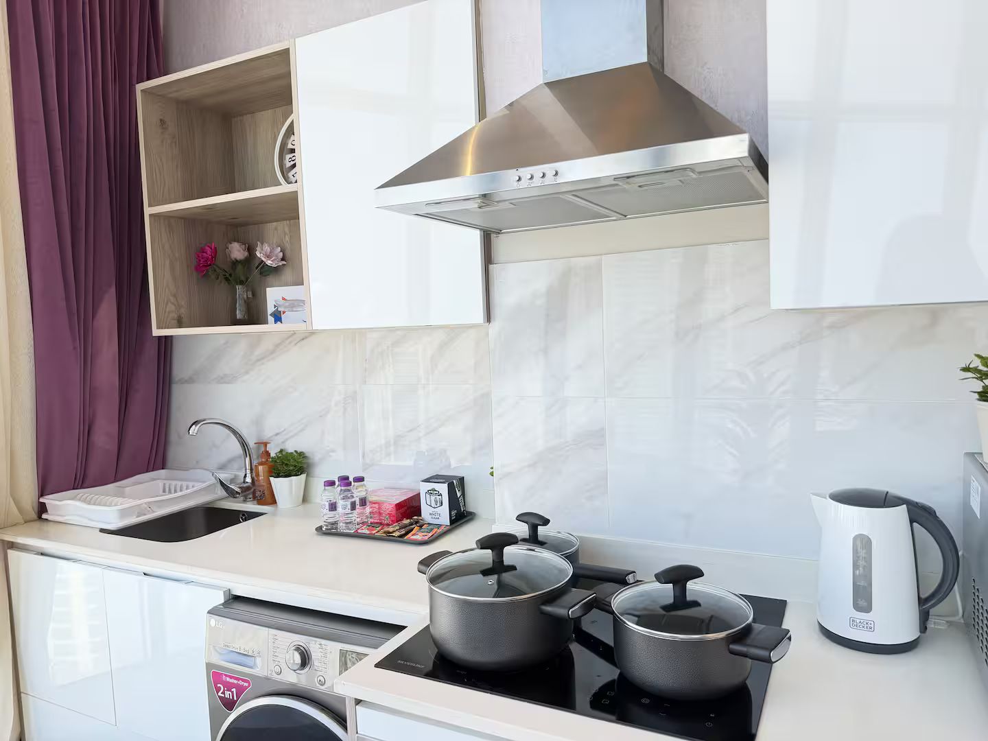 Une cuisine moderne équipée d’un four encastré, d’une cuisinière et d’une bouilloire.