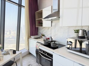 A modern kitchen with a large window, a stove, a sink, and a countertop with various items.