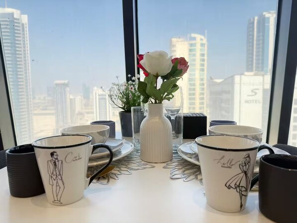 A table with a vase of flowers and a city view.