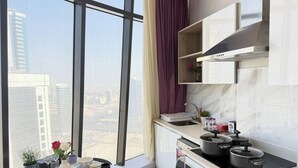 A modern kitchen with a large window, a dining table set with dishes, and a stove. - High-Floor Sea View Studio - Seef Area F296O (Seef)
