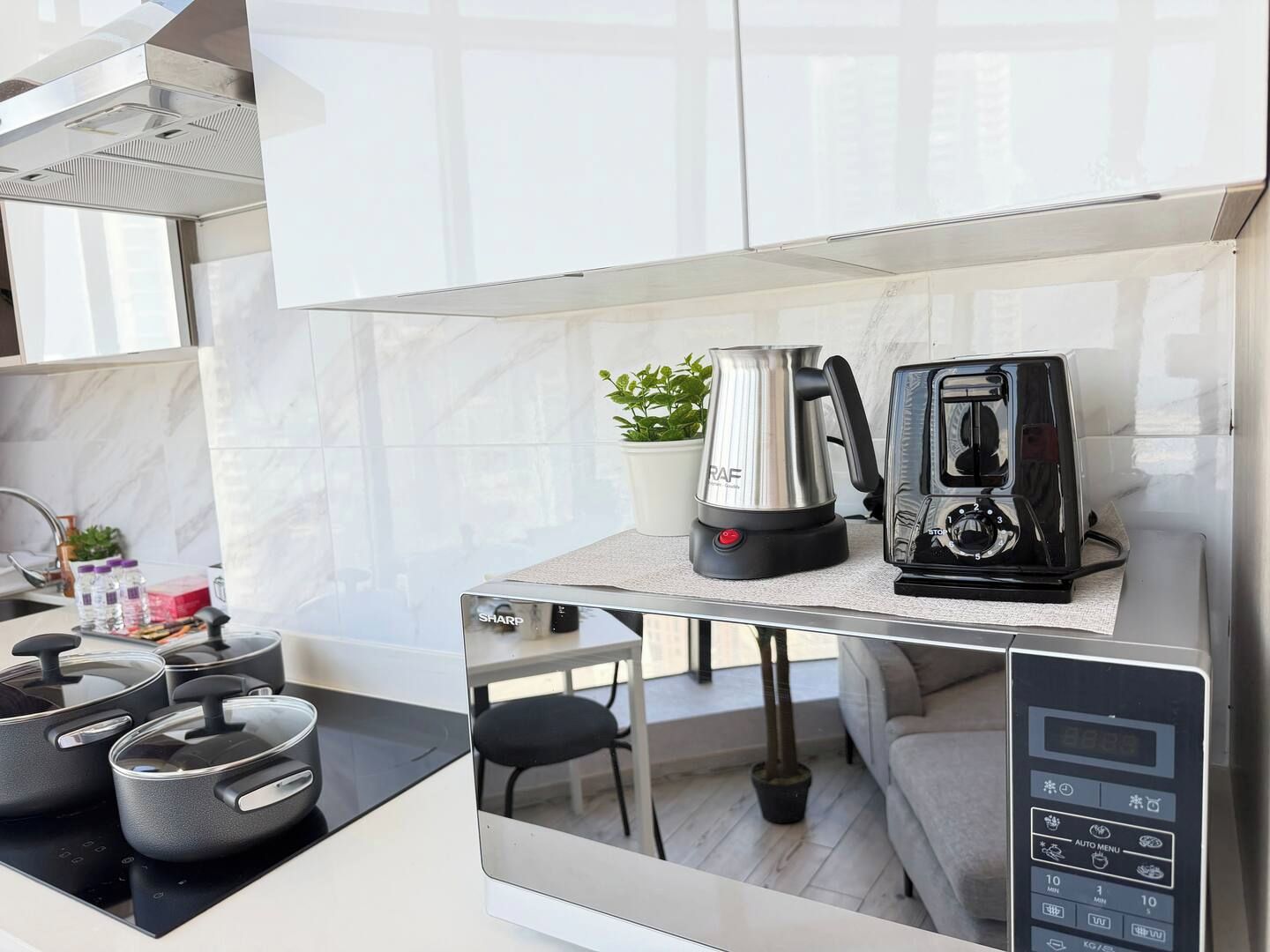 Une cuisine moderne équipée d’une cuisinière intégrée, d’une bouilloire et d’une machine à café, le tout posé sur un plan de travail.