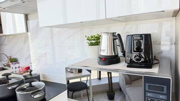 Une cuisine moderne équipée d’une cuisinière intégrée, d’une bouilloire et d’une machine à café, le tout posé sur un plan de travail.