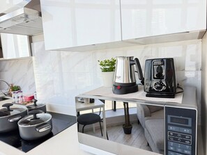 A modern kitchen with a built-in stove, a kettle, and a coffee maker on a countertop.