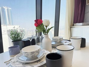 A dining table set with plates, bowls, and a vase with flowers.