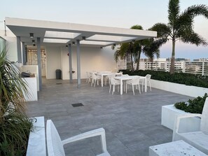 An outdoor patio area with white wicker furniture, a covered seating area, and a view of the cityscape. -  Luxury Designer-Furnished 2BR with 2 Large Terraces in Bay Harbor (Bay Harbor Islands)