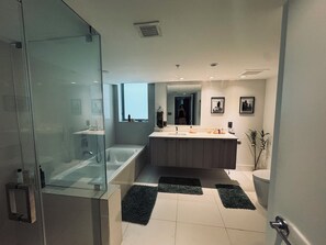 Een moderne badkamer met een douchecabine van glas, een vrijstaand bad, een wastafelmeubel met een wastafel en een toilet.