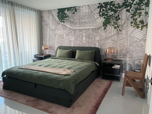 Een slaapkamer met een groot bed, twee nachtkastjes, een houten stoel en een muur met een kaartontwerp.