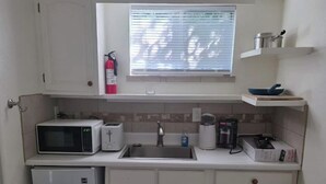 Eine kompakte Küche mit Mikrowelle, Toaster, Spüle und einem kleinen Kühlschrank.