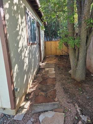 A stone pathway leading to a house with a wooden fence and a tree. - King size studio with ensuite bathroom, kitchenette and private entrance. West Sedona neighborhood close to hiking, trails, shopping, restaurants and vortex. (Sedona)
