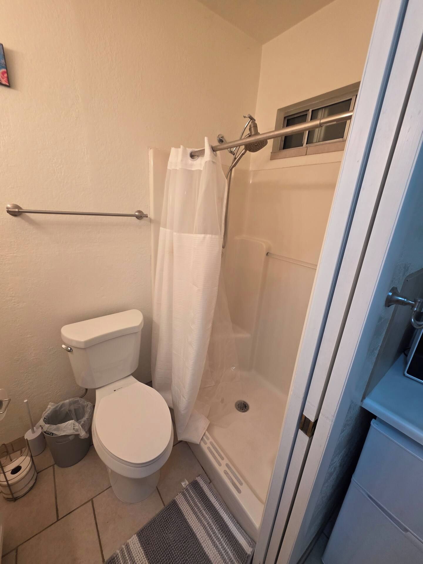 A bathroom with a toilet, shower, and a towel rack.