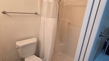 A bathroom with a toilet, shower, and a towel rack.