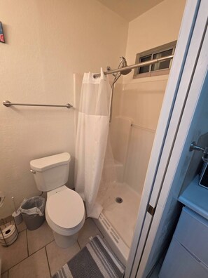 Un baño con inodoro, ducha y un perchero para toallas.