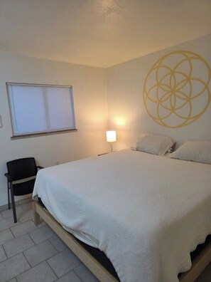 A bedroom with a bed, a chair, a lamp, and a window with blinds. - King size studio with ensuite bathroom, kitchenette and private entrance. West Sedona neighborhood close to hiking, trails, shopping, restaurants and vortex. (Sedona)