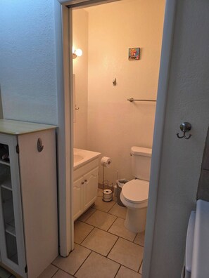 Een kleine badkamer met toilet, wastafel en een klein kastje.