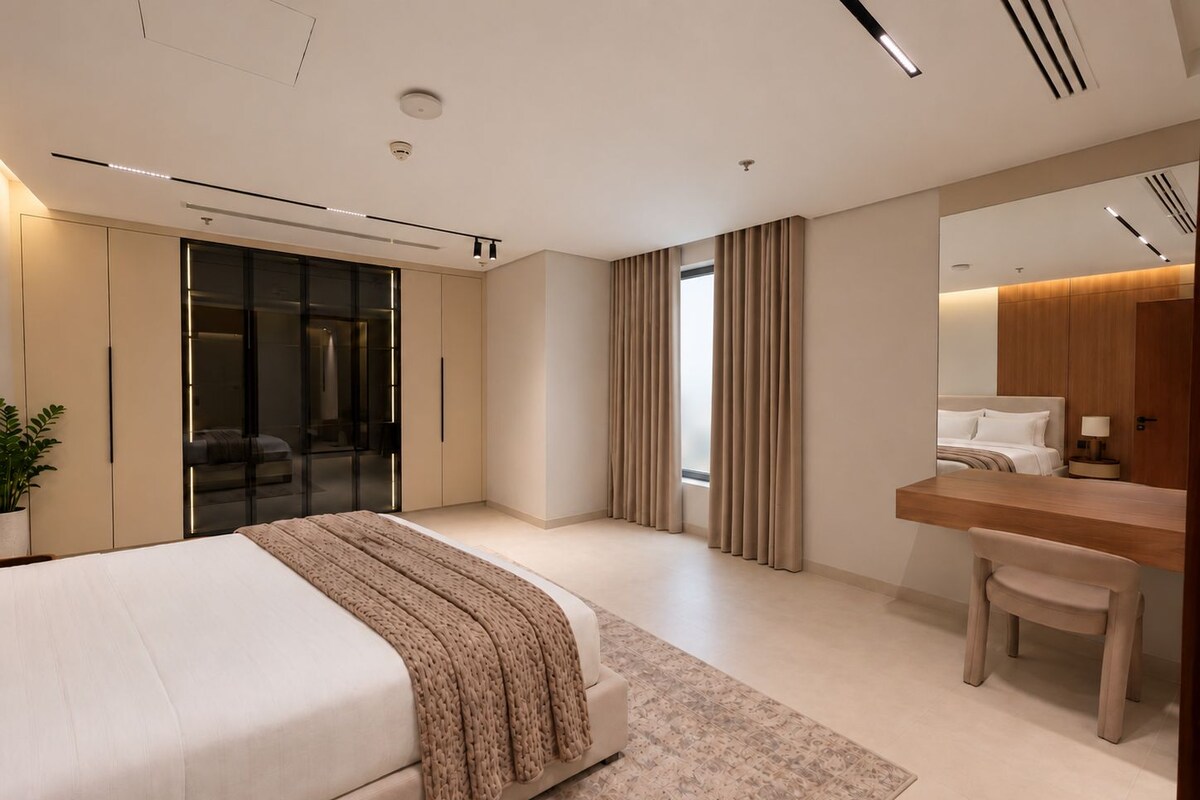 A modern bedroom with a bed, a desk, and a mirror.