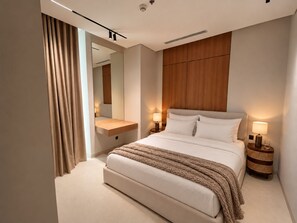 Ein modernes Hotelzimmer mit einem großen Bett, Nachttischlampen, einem Holzkopfstück, einem Spiegel und einem Nachttisch.
