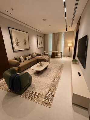 Uma sala de estar moderna com sofá seccional, mesa de centro, televisão e tapete estampado.