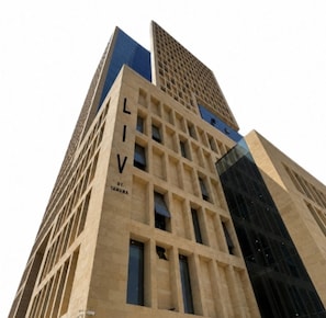 Ein hohes Gebäude mit einer gitterartigen Fassade und dem Schriftzug 'LIV' an der Seite.