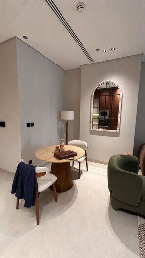 A modern interior with a round table, chairs, a lamp, and a green armchair. - LIV by Yamama - Park 91 (Riyadh)