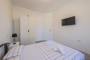 A hotel room with a bed, a TV mounted on the wall, a desk with a lamp, and a wardrobe. - A2 - spacious apartment on seafront with the sea view (Kaštel Stari)
