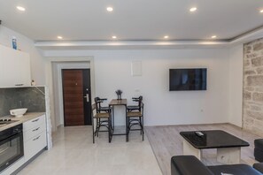 A modern kitchen with white cabinets, a built-in oven, and a dining area with a wooden table and chairs. - A2 - spacious apartment on seafront with the sea view (Kaštel Stari)