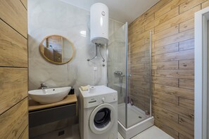 Uma casa de banho moderna com lavatório, espelho, sanita e cabine de duche com vidro.