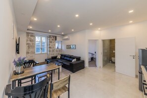 Ein modernes Wohnzimmer mit einer schwarzen Ledersofa, einem Holzesstisch und einer Wand als Steinakzent.