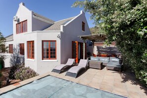 A two-story house with a swimming pool, outdoor seating, and a covered patio area. - Spacious 4-bedroom house in amazing Cape Town with AC (Cape Town)