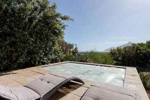 Zona de piscina con sillones de descanso y vista al océano.