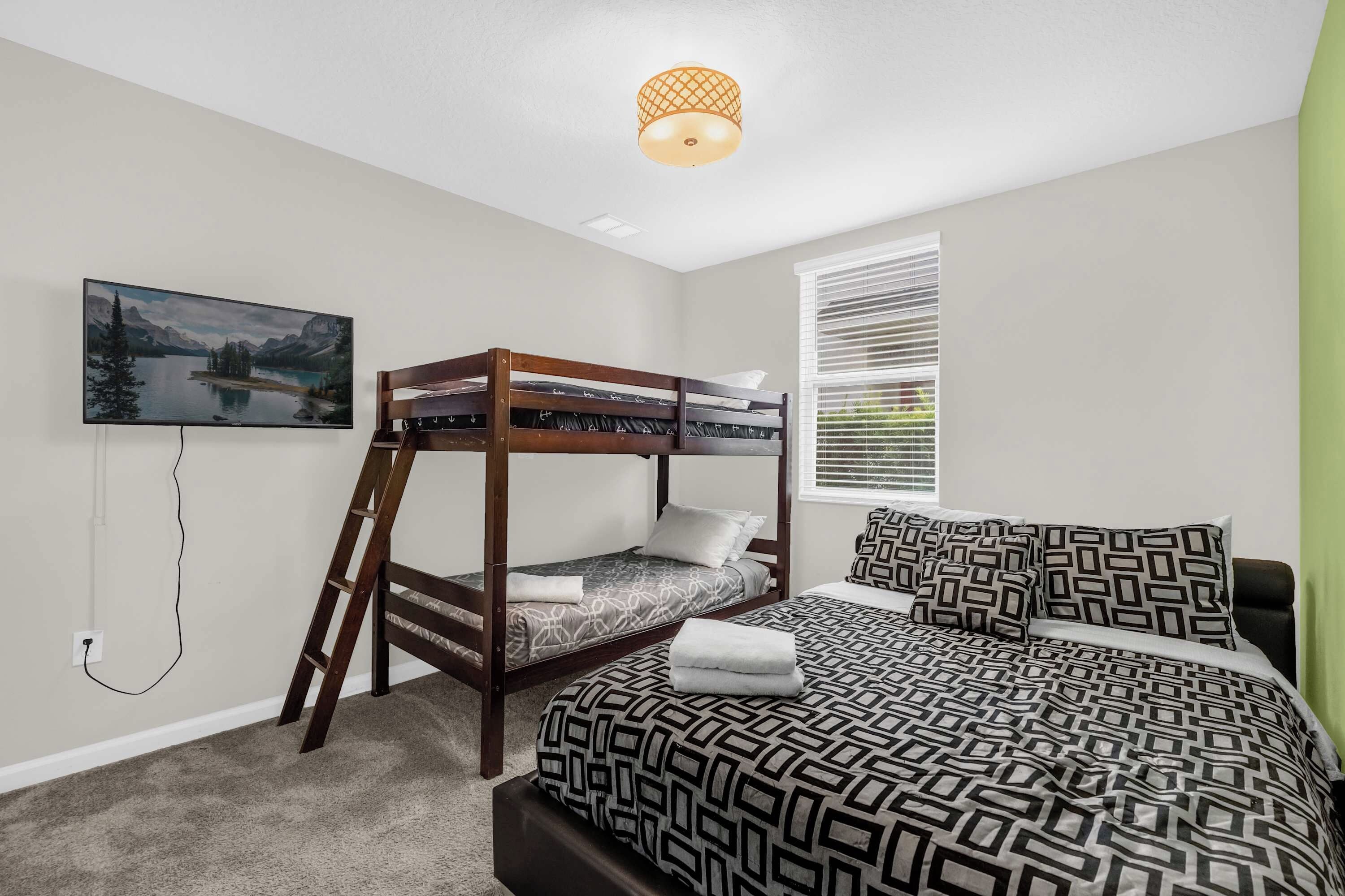 Quarto com cama beliche, televisão de tela plana, janela com persianas e um quadro na parede.