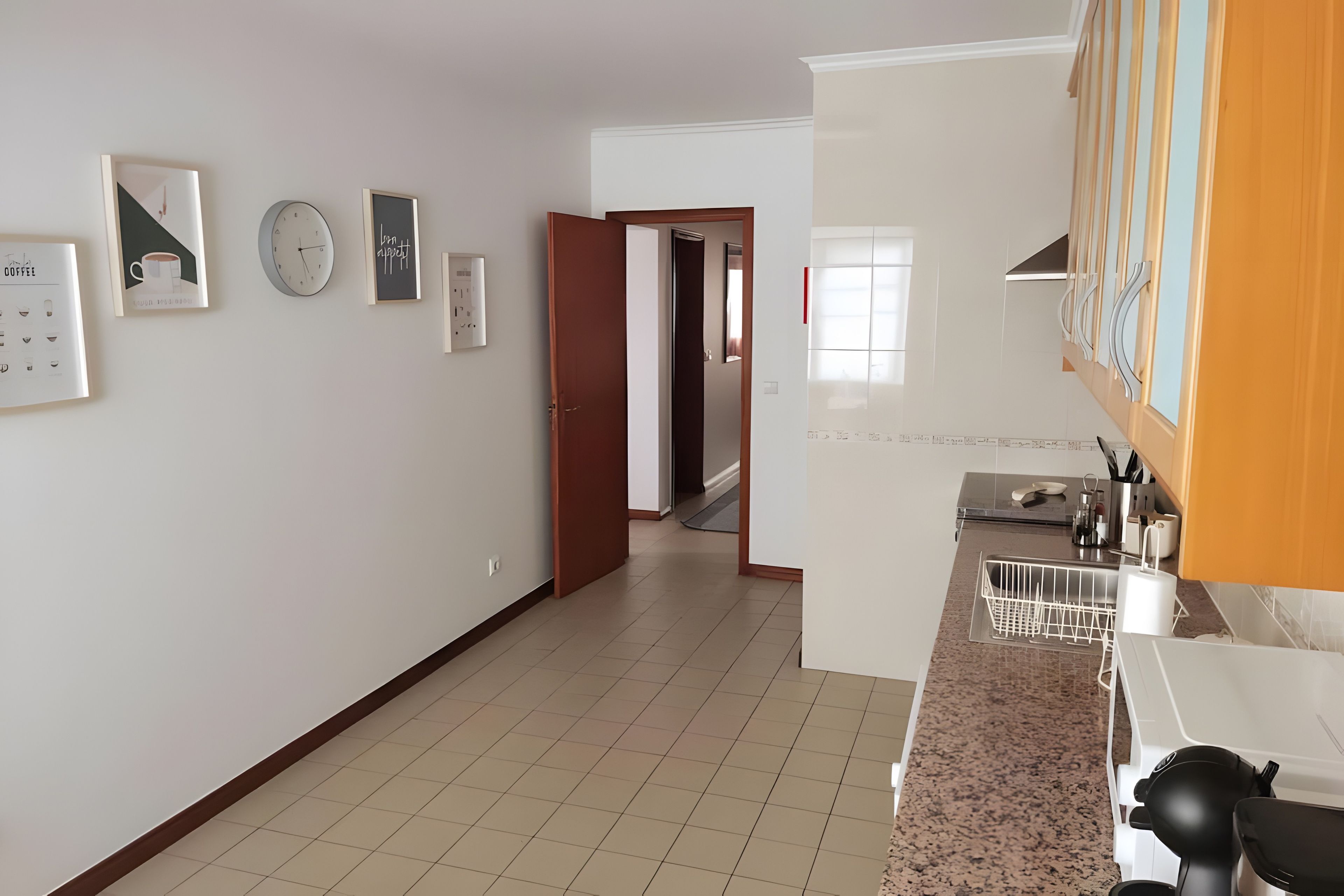 Cozinha com bancada, pia e porta para outro cômodo.
