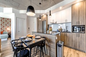 A modern kitchen with a central island, wooden cabinets, and pendant lighting. - El Emilio · Parking · Piscine et spa · 2 chambres (Quebec City)