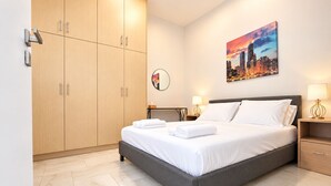 Una habitación de hotel moderna con una cama, mesitas de noche, un armario y un cuadro de un paisaje urbano en la pared.